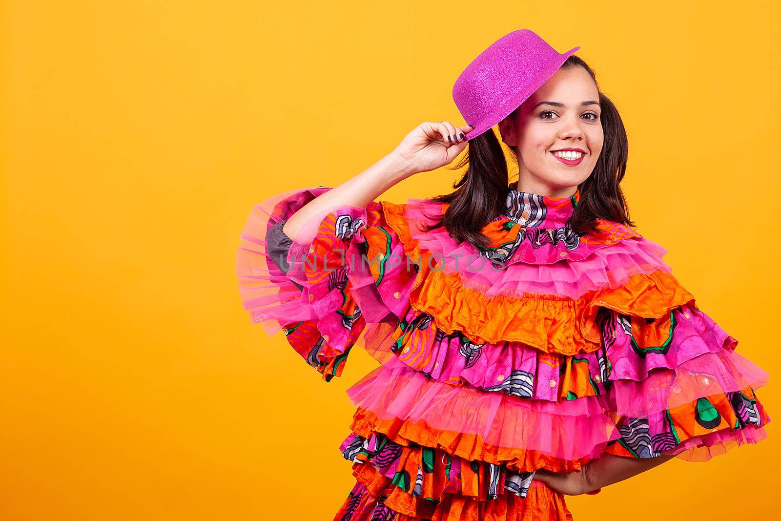 Young beautiful woman wearing a mascarade latino costume over yellow background in studio