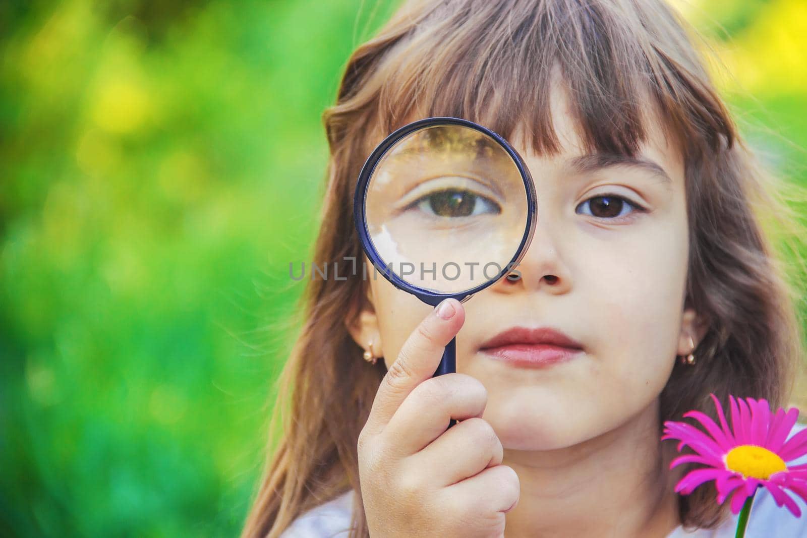 The child is looking in a magnifying glass. Increase. selective focus.