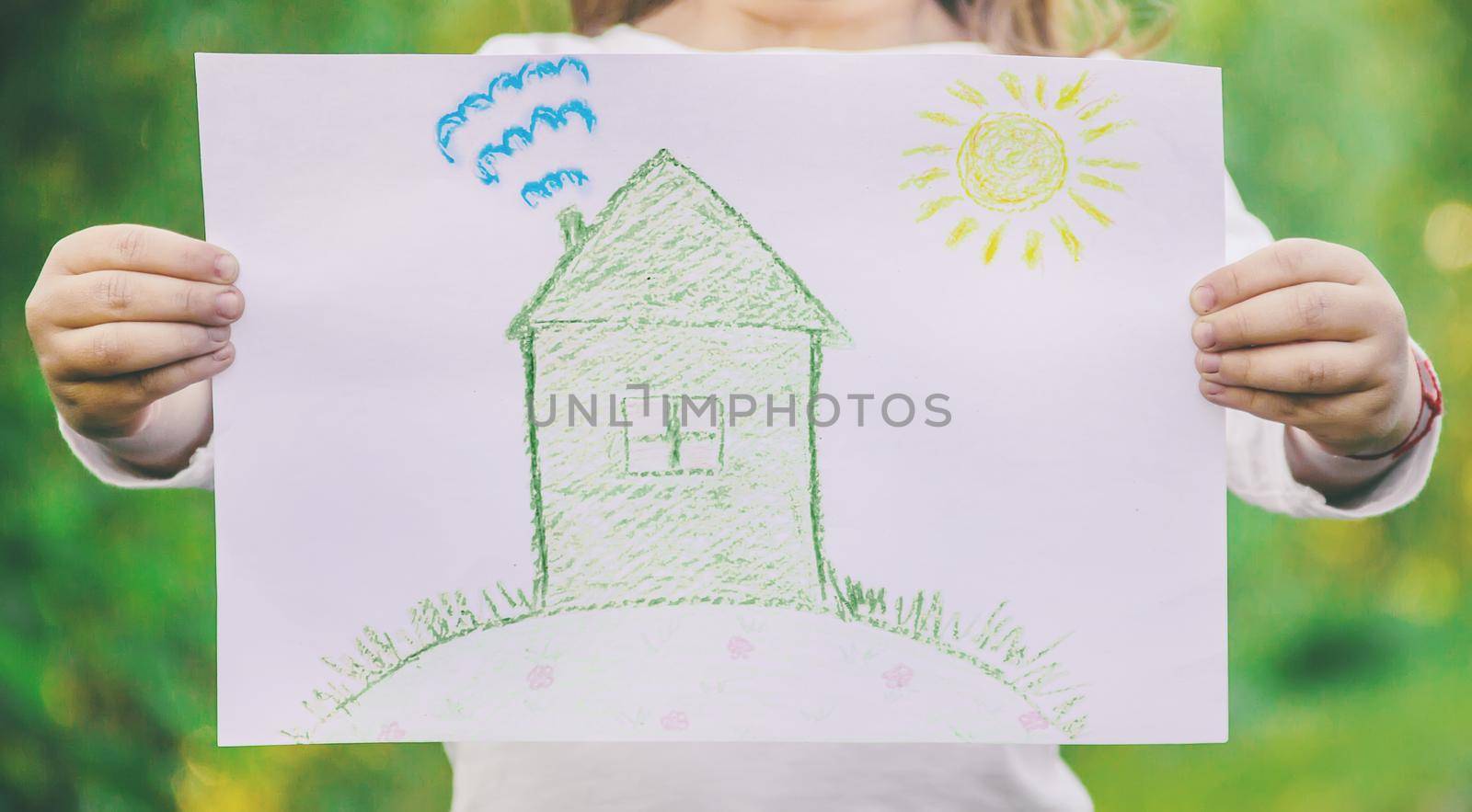 Drawing of a green house in the hands of a child. nature.l