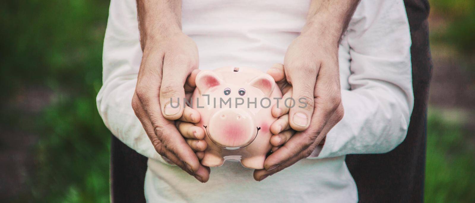 The child and parents are holding a piggy bank in their hands.