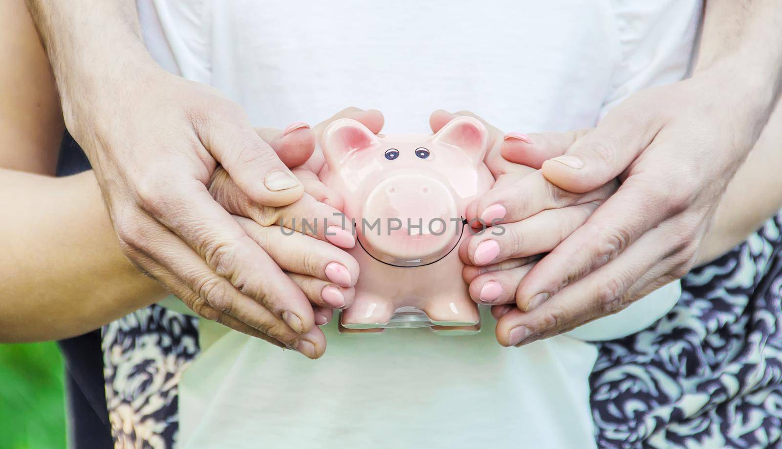 The child and parents are holding a piggy bank in their hands. nature.