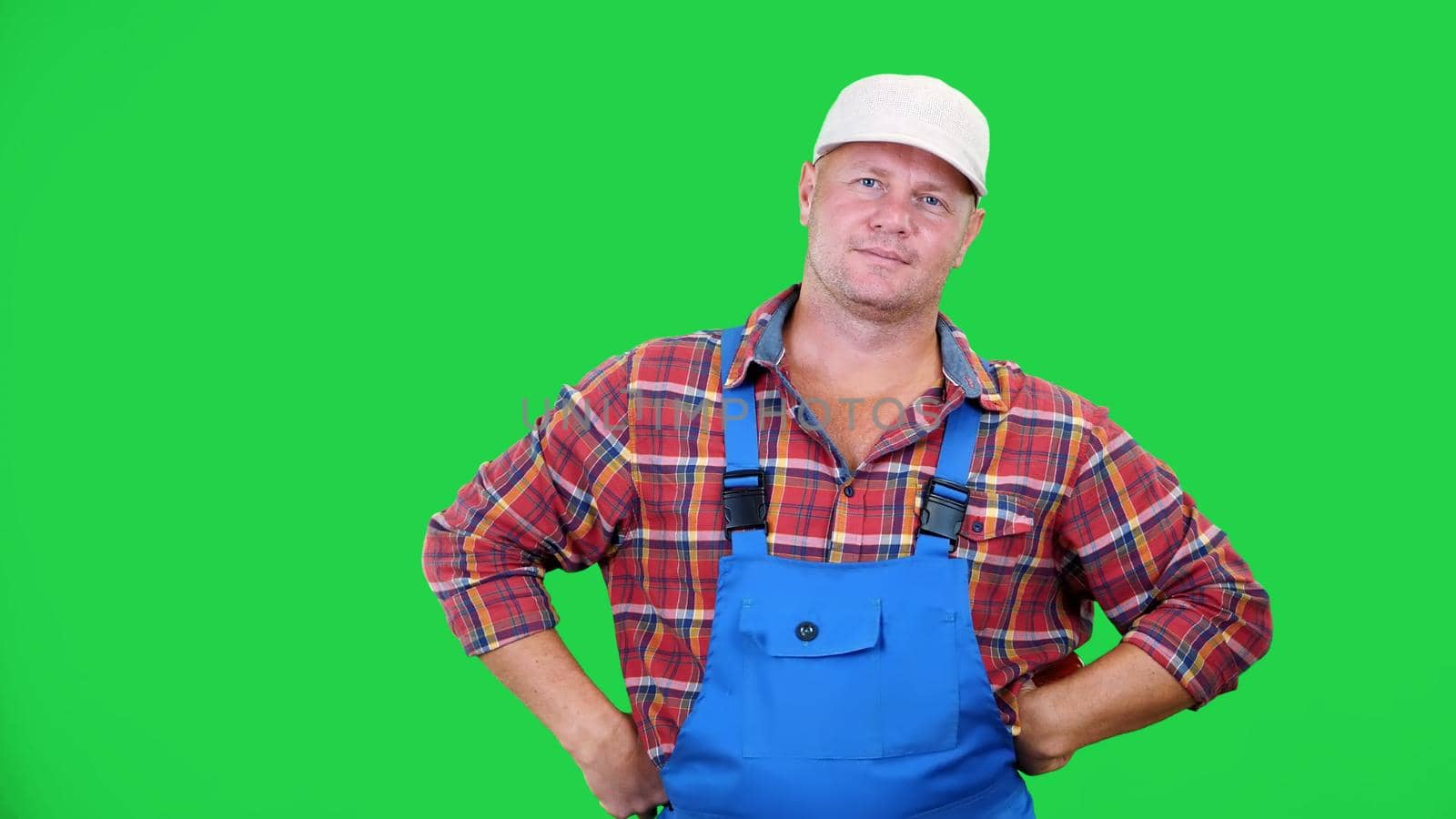 smiling male farmer in plaid shirt and hat holds beautiful sweet pepper,playing, throws it, on Chromakey, green background. concept of Healthy food to your table. High quality photo