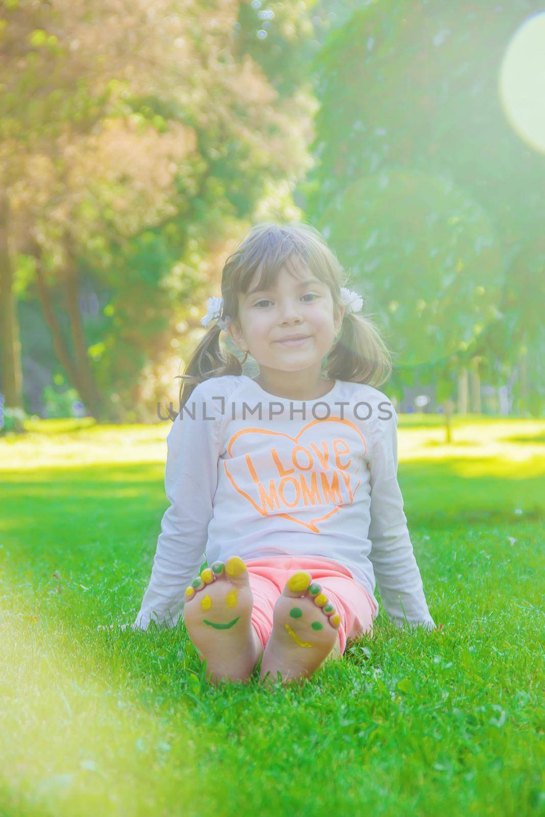 Child lying on green grass. Kid having fun outdoors in spring park.