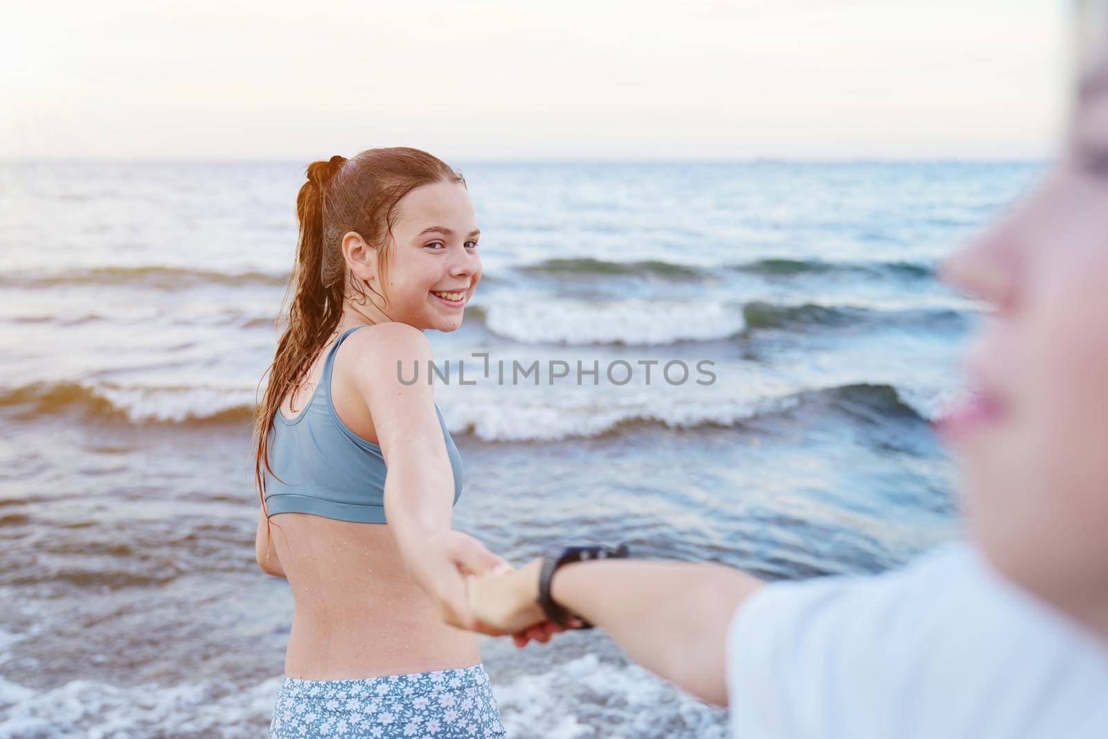follow me swimming. Smiling girl standing at sea and invites you to swim, follow me travel concept. Young woman in follow me pose enjoying the summer.