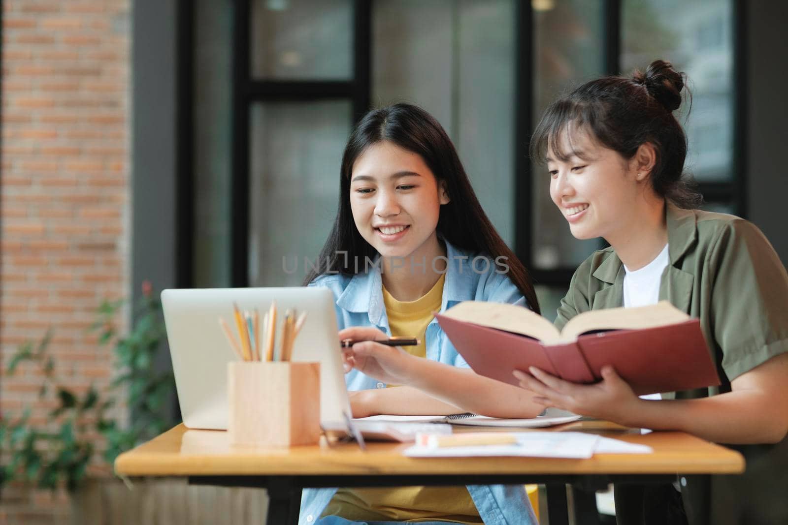 Two Young woman studying for a test or an exam. Tutor books with friends. Young students campus helps friend catching up and learning.