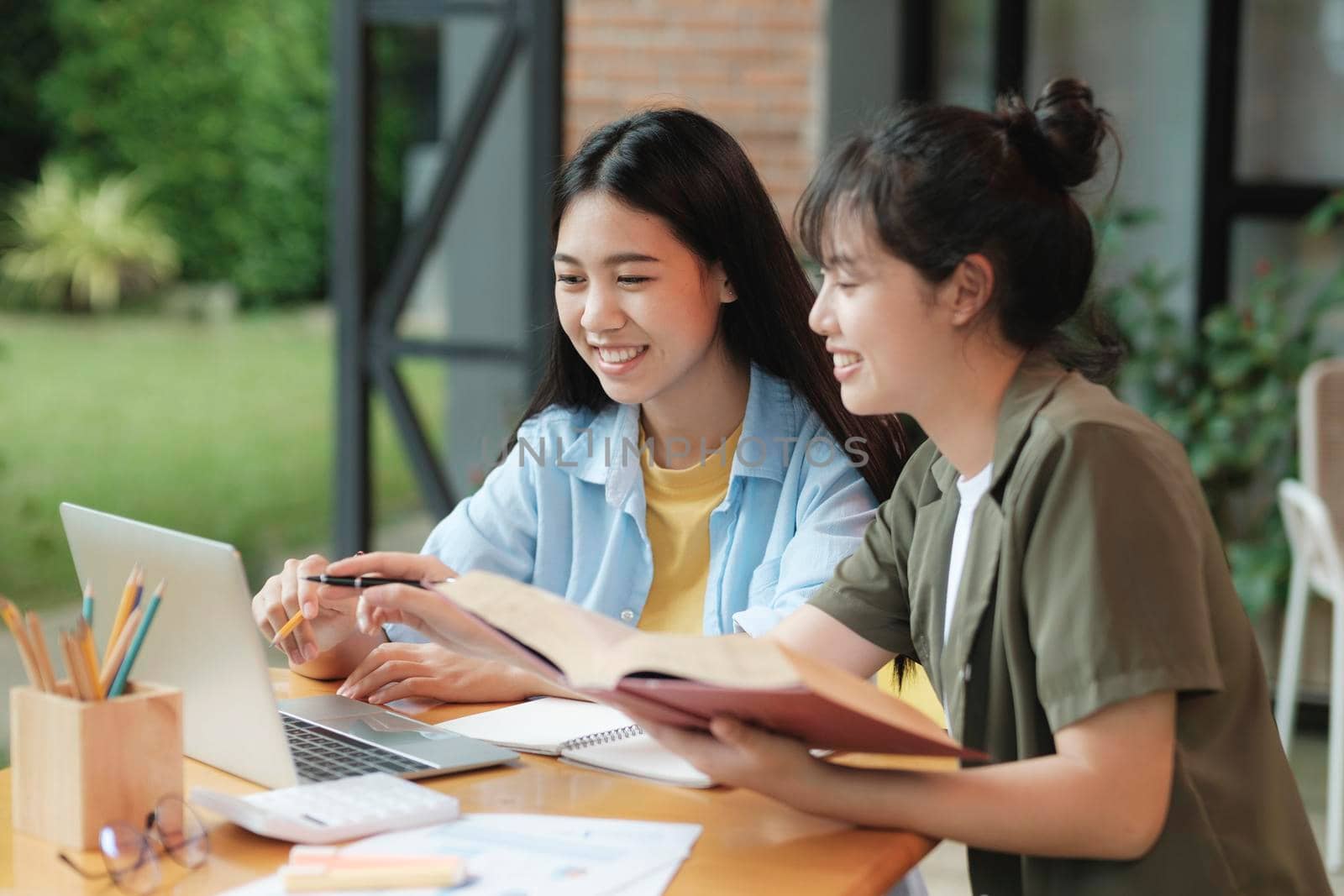 Two Young woman studying for a test or an exam. Tutor books with friends. Young students campus helps friend catching up and learning.