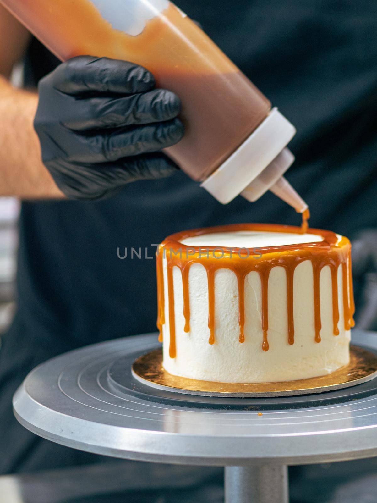 professional baker decorating a chocolate and cream cake with salty caramel