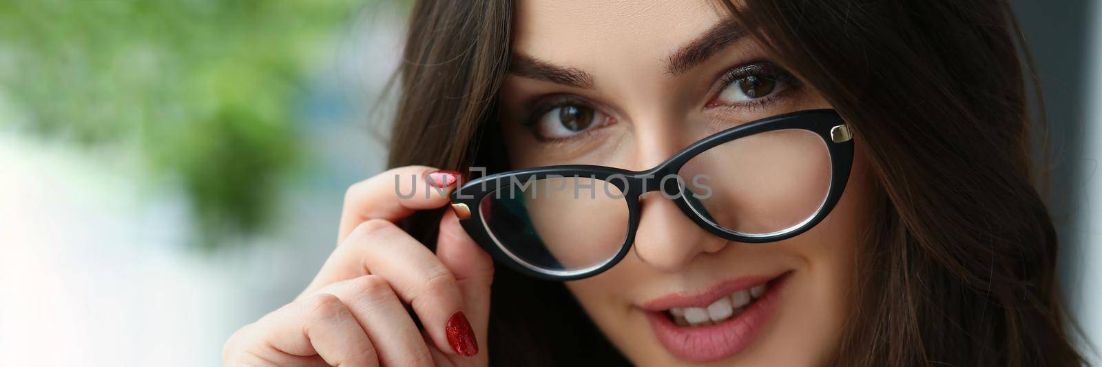 Portrait of beautiful brunette adult woman touch glasses frame, attractive young female with flirty look posing. Professional model, beauty, style concept
