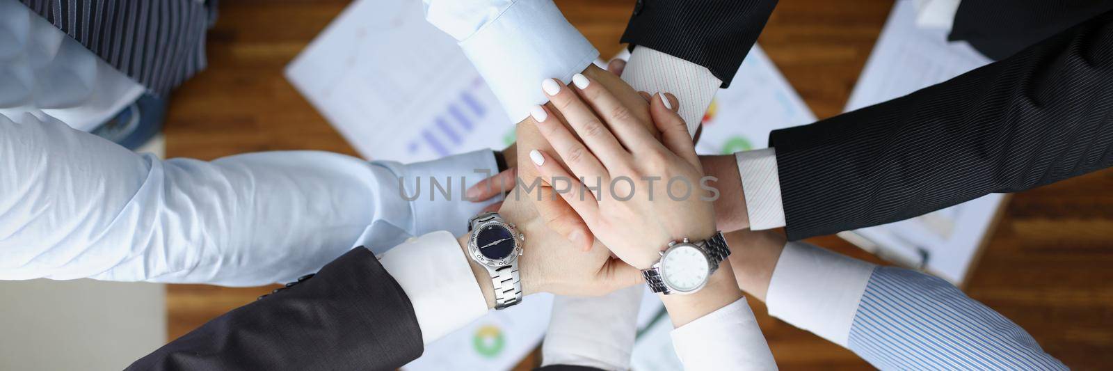 Top view of colleagues performing gesture in order to prepare for important profitable project, change future of corporation. Teamwork, business concept