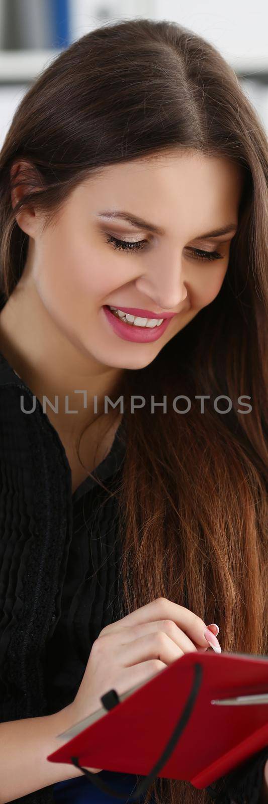 Portrait of woman holding silver pen ready to make note in opened notebook sheet. Businesswoman in suit at workspace with organizer diary. Creative concept