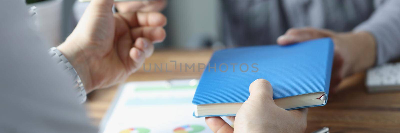 Close-up of businesspeople exchange notebooks in office, men give to each other books. Share knowledge, useful information. Business, reading, note concept