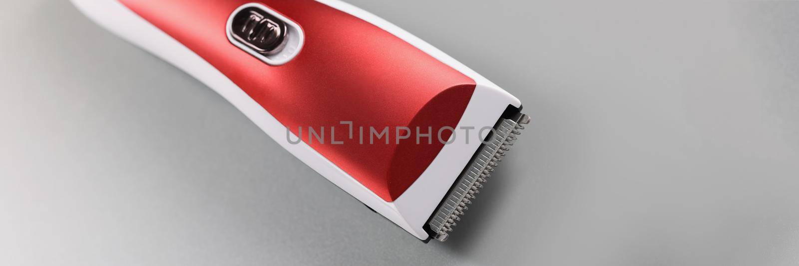 Electric hair machine for trimming hair, red colour design on grey surface by kuprevich