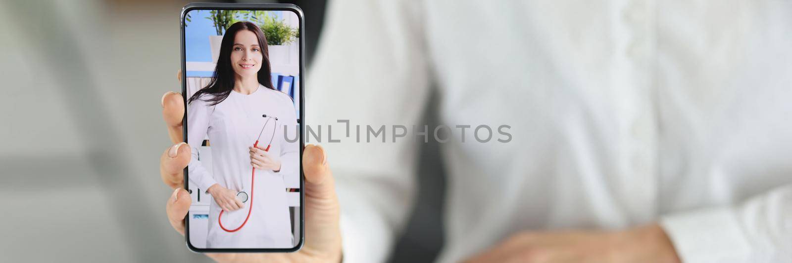 Close-up of woman office worker show smartphone with doctor woman on screen, change qualification. Brave enough to change profession. Retraining concept