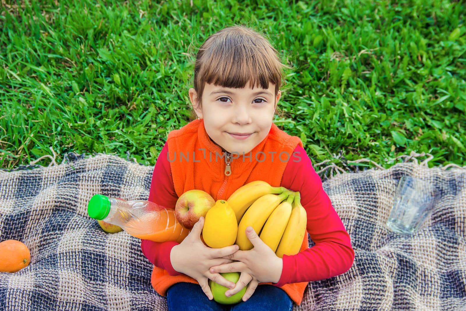 Child on a picnic with juice and fruit. Selective focus. by yanadjana