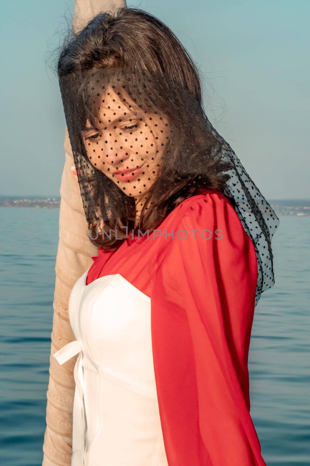 Attractive middle-aged woman in a red dress on a yacht on a summer day. Luxury summer adventure, outdoor activities. by Matiunina