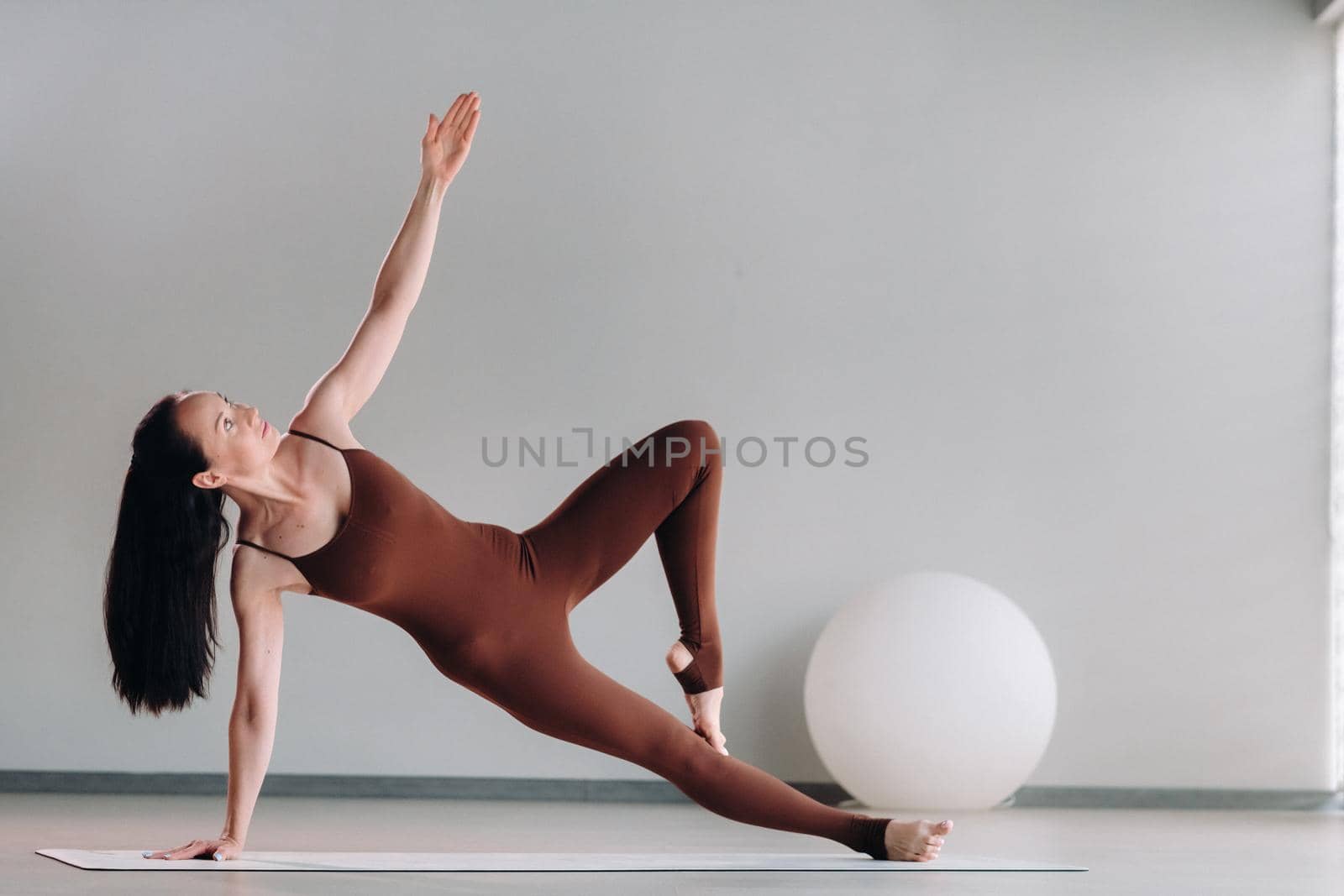 a woman in a brown suit does yoga in a fitness room . Healthy lifestyle, fitness, training, self-care.