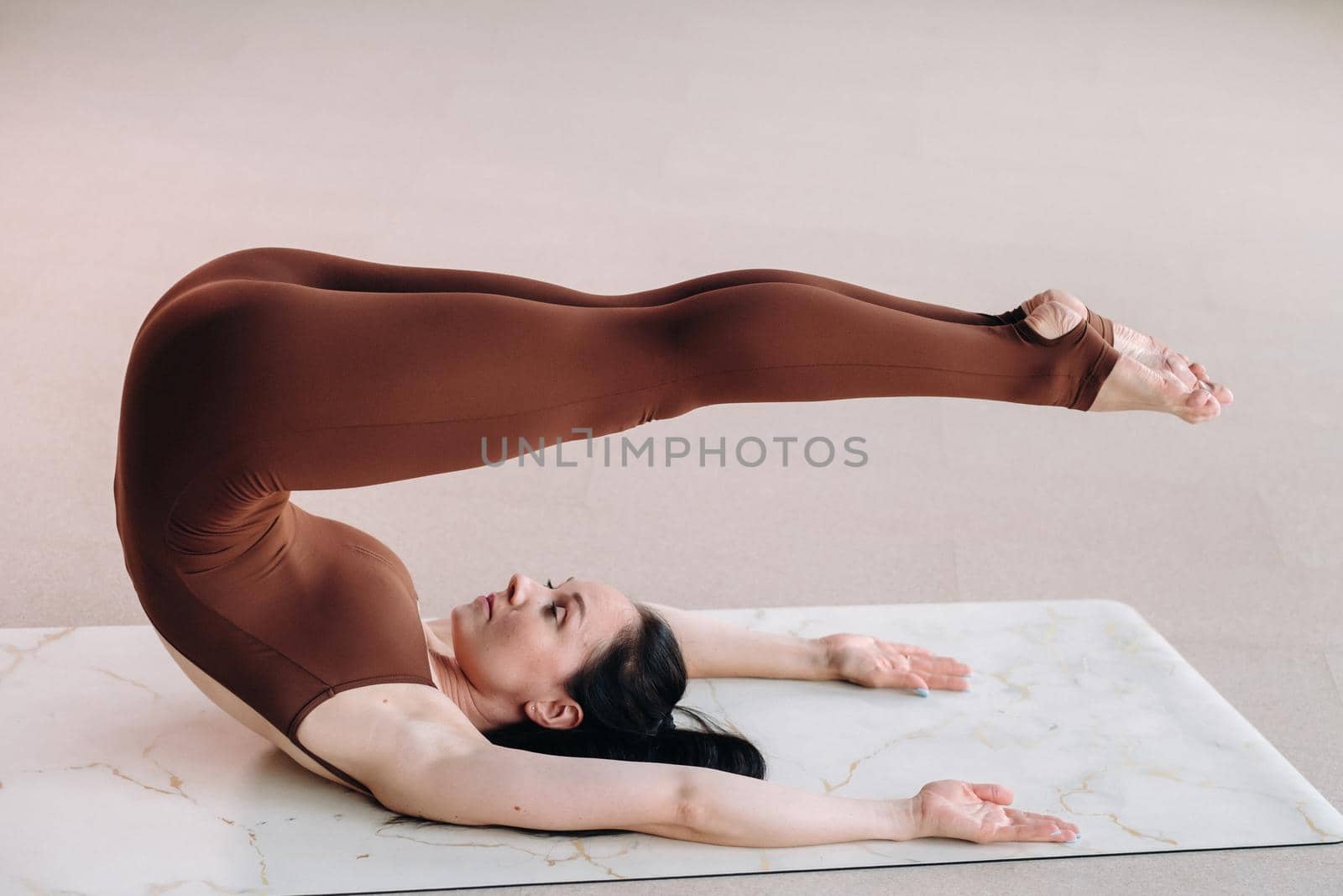 a woman in a brown suit does yoga in a fitness room . Healthy lifestyle, fitness, training, self-care.