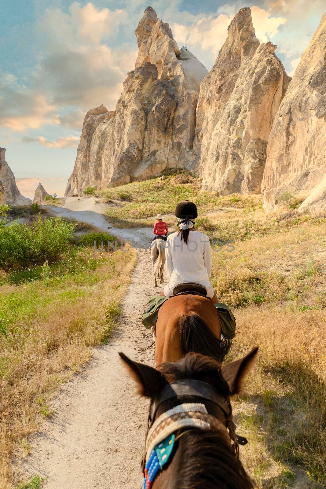 young woman during a vacation in Turkey Kapadokya watching the hot air balloons of Cappadocia. Asian women on the back of a brown horse in the valley of Cappadocia