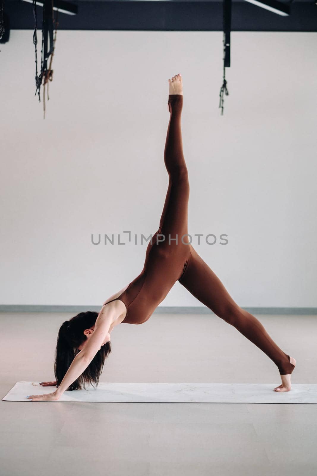 a woman in a brown suit does yoga in a fitness room . Healthy lifestyle, fitness, training, self-care.