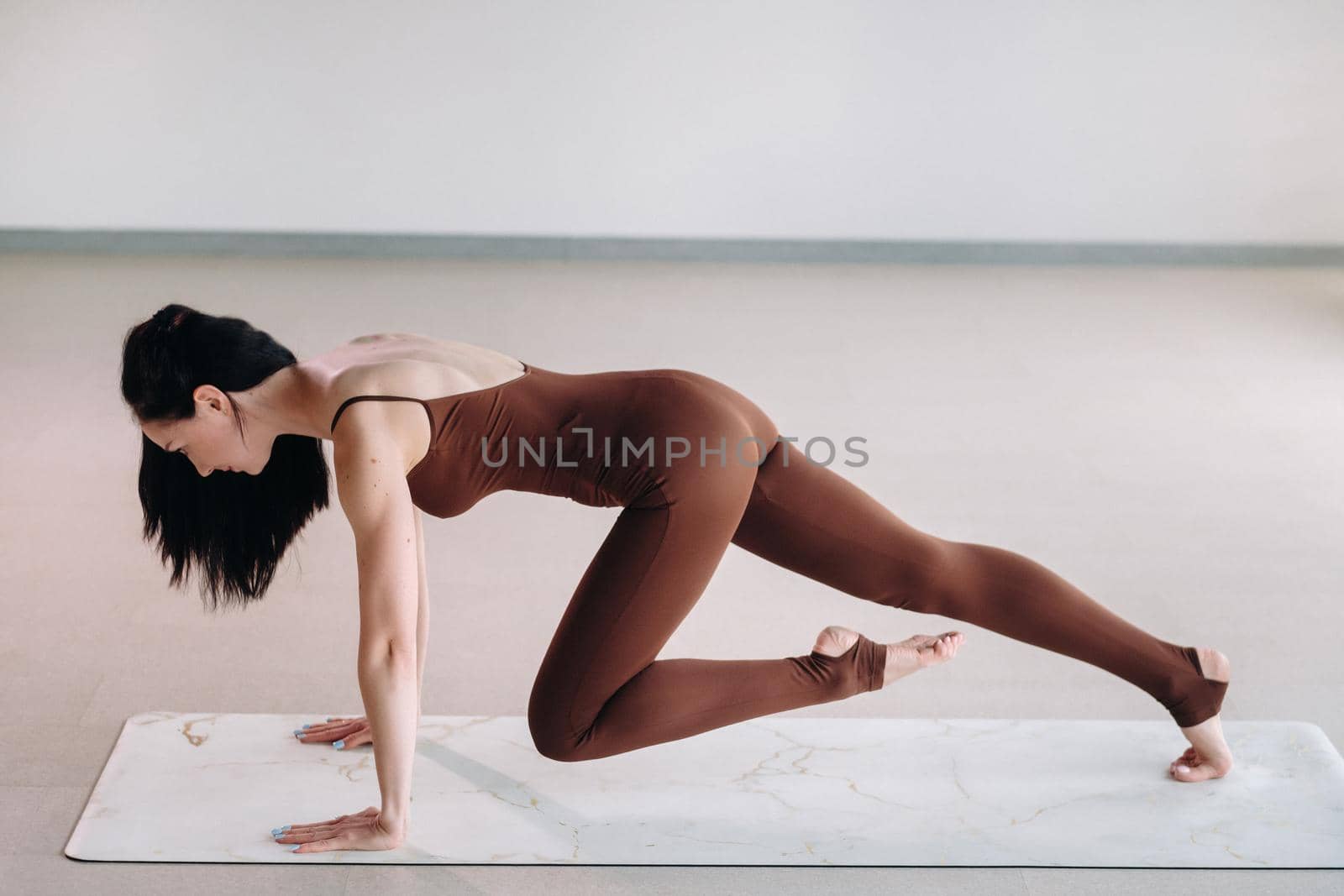 a woman in a brown suit does yoga in a fitness room . Healthy lifestyle, fitness, training, self-care.