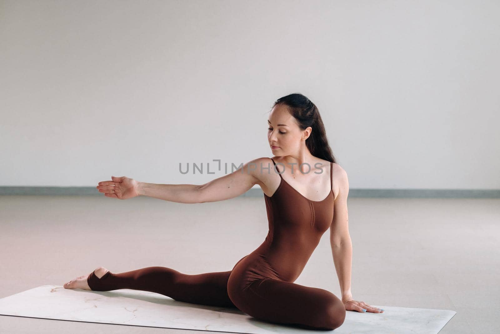 a woman in a brown suit does yoga in a fitness room . Healthy lifestyle, fitness, training, self-care.