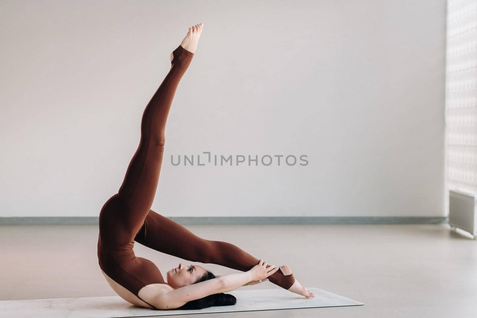 a woman in a brown suit does yoga in a fitness room . Healthy lifestyle, fitness, training, self-care.