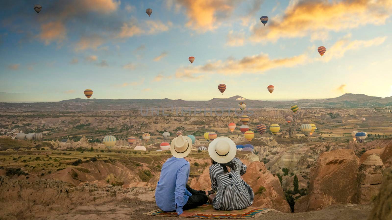 happy young couple during sunrise watching the hot air balloons of Kapadokya Cappadocia Turkey by fokkebok