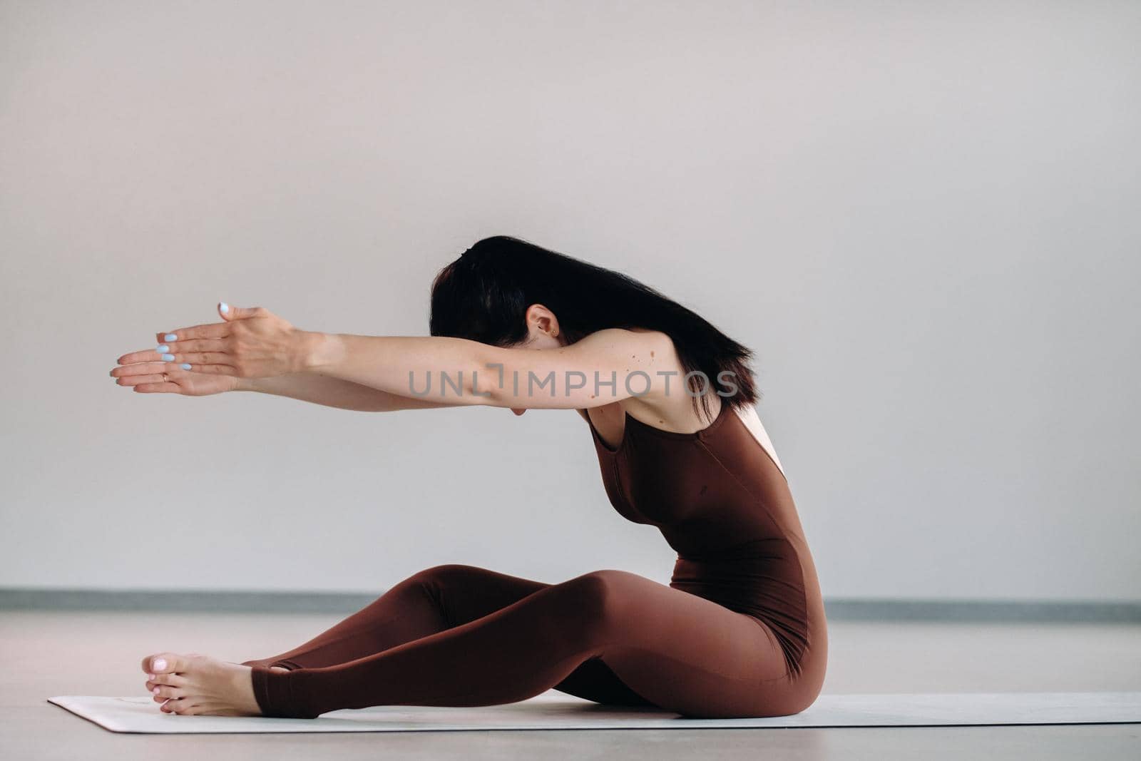 a woman in a brown suit does yoga in a fitness room . Healthy lifestyle, fitness, training, self-care.