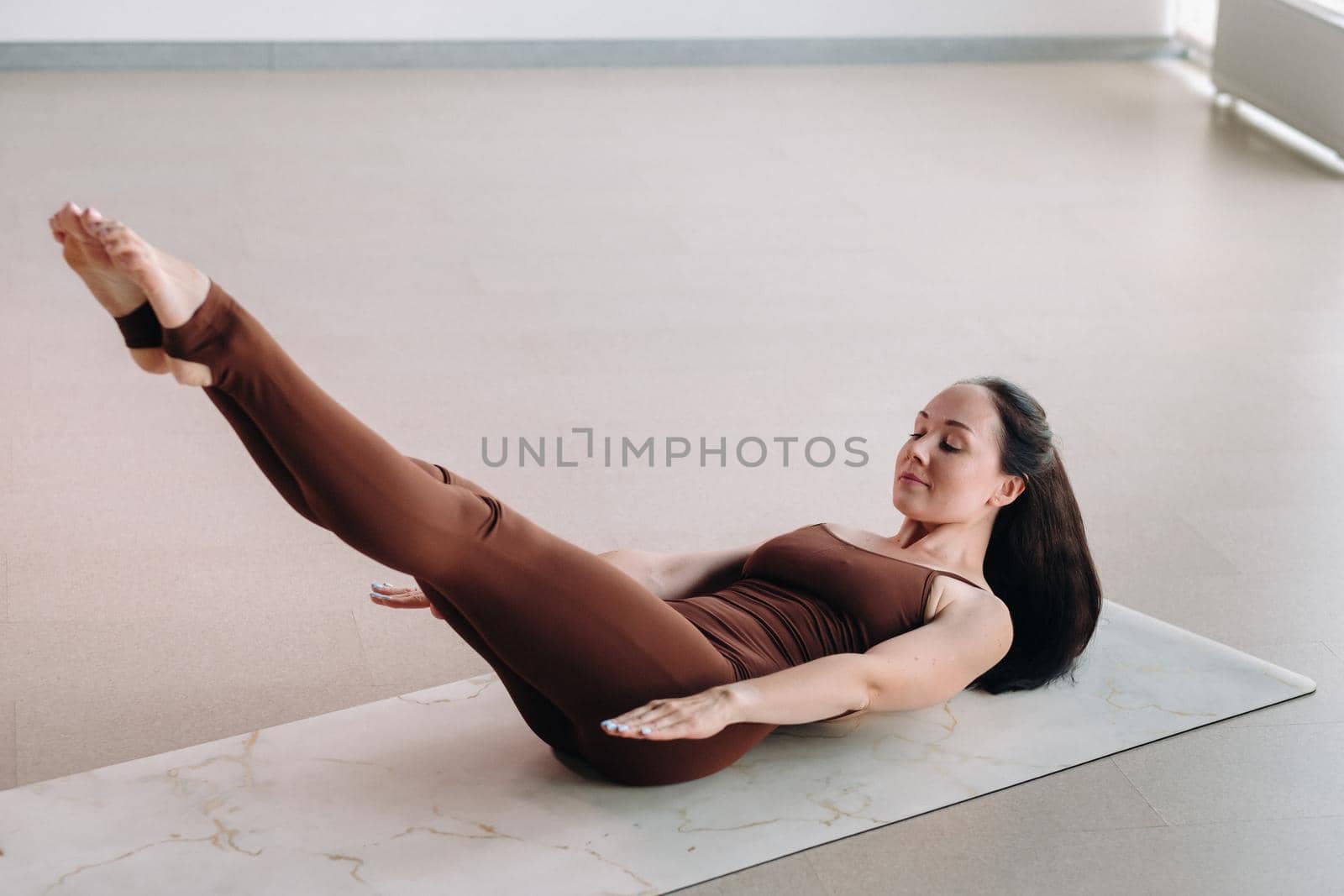 a woman in a brown suit does yoga in a fitness room . Healthy lifestyle, fitness, training, self-care.