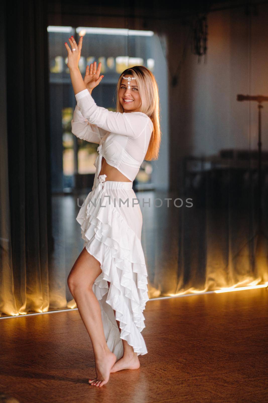 Beautiful smiling girl in a white dress dancing in the gym.