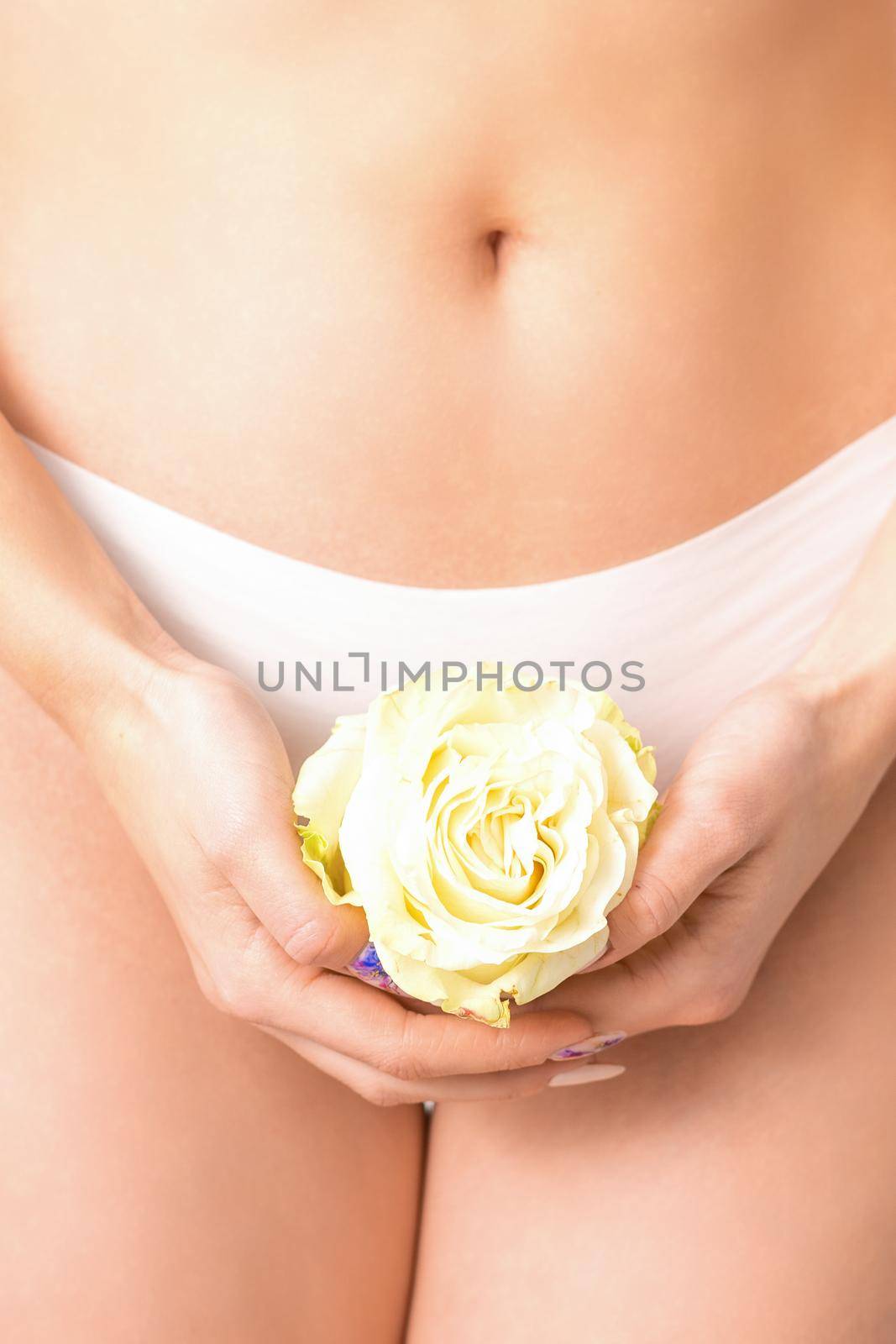 Caucasian woman in white panties with white rose flower on a uniform background, closeup. by okskukuruza