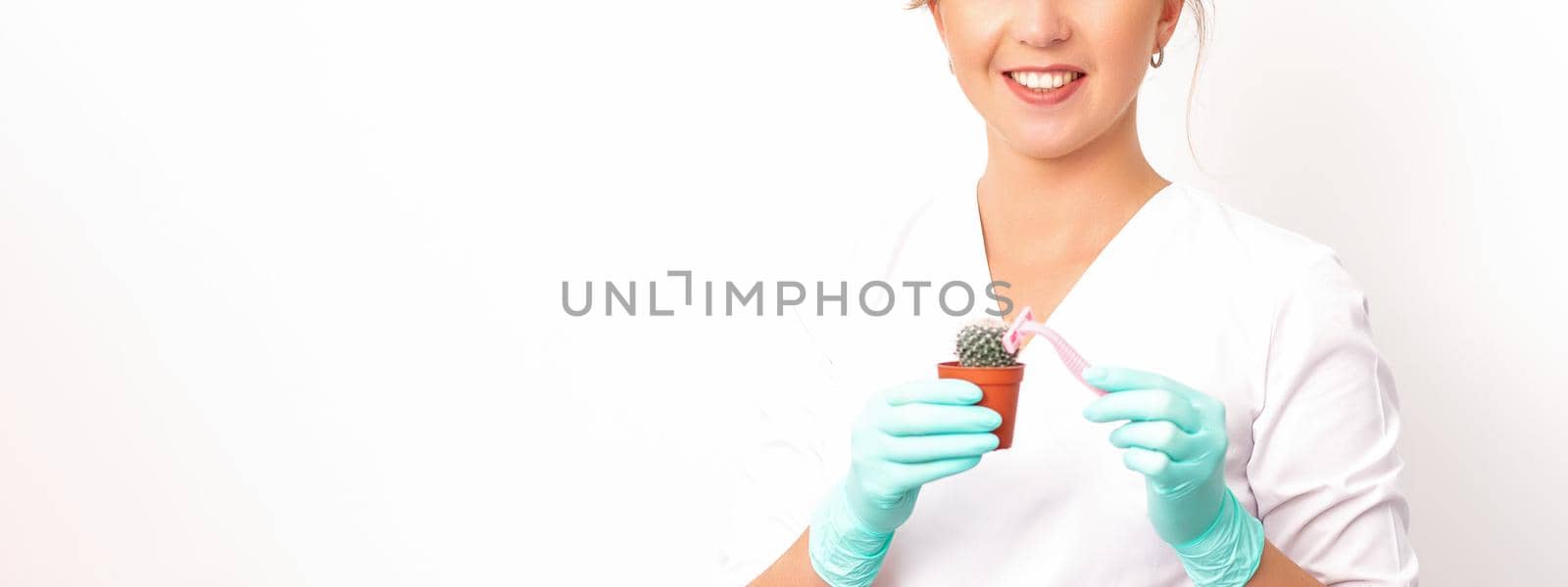 A smiling female beautician holds little green cactus with the razor in her hands. Hair removal concept