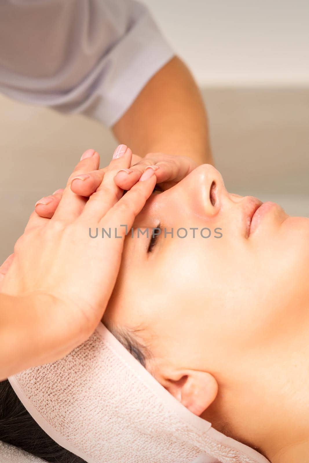 Facial massage. Young caucasian woman with closed eyes getting a massage on her forehead in a beauty salon