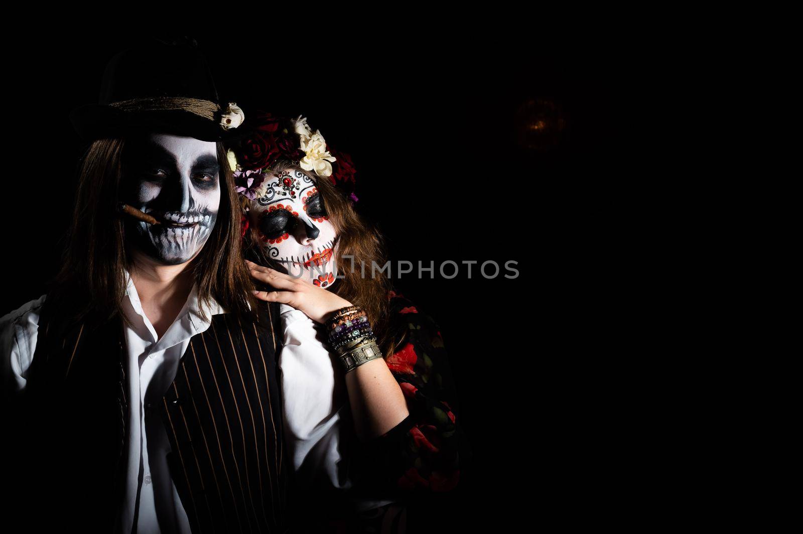 Woman in santa muerte costume and man in skeleton bodypainting for halloween