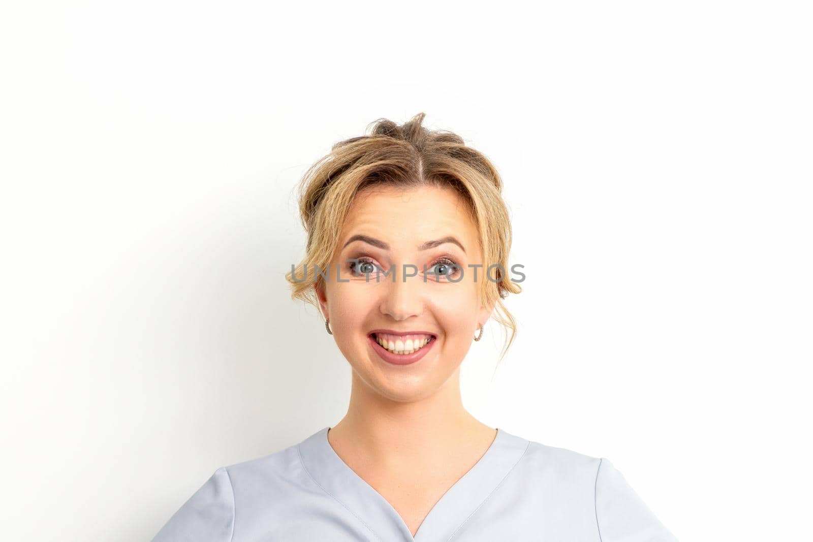 Portrait of a young caucasian happy woman doctor wearing blue workwear smiling against the white background