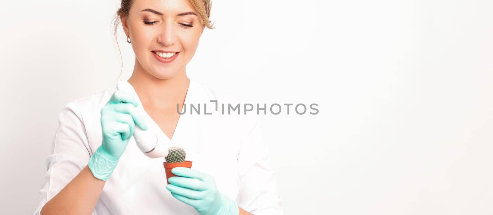 A smiling female beautician holds little green cactus with the razor in her hands. Hair removal concept