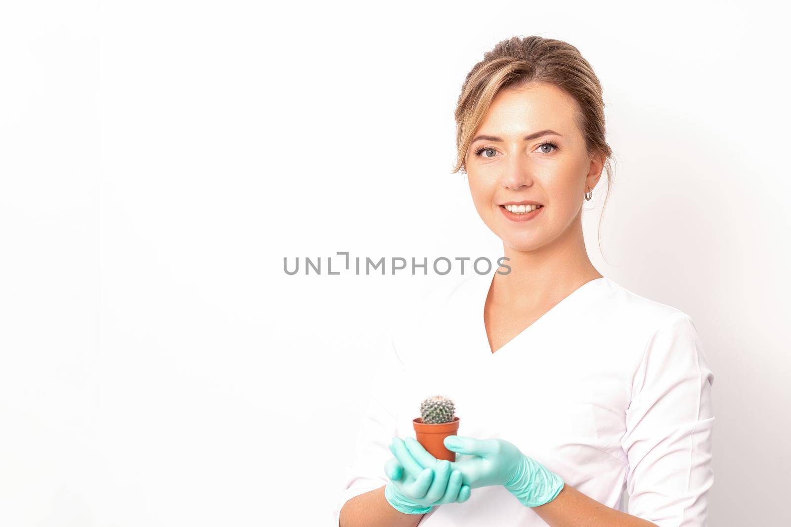 A portrait of a smiling female holds little green cactus in her hands. Hair removal concept