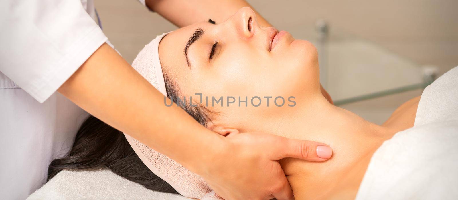 Facial massage. Young caucasian woman getting a massage on her neck in a beauty clinic. by okskukuruza