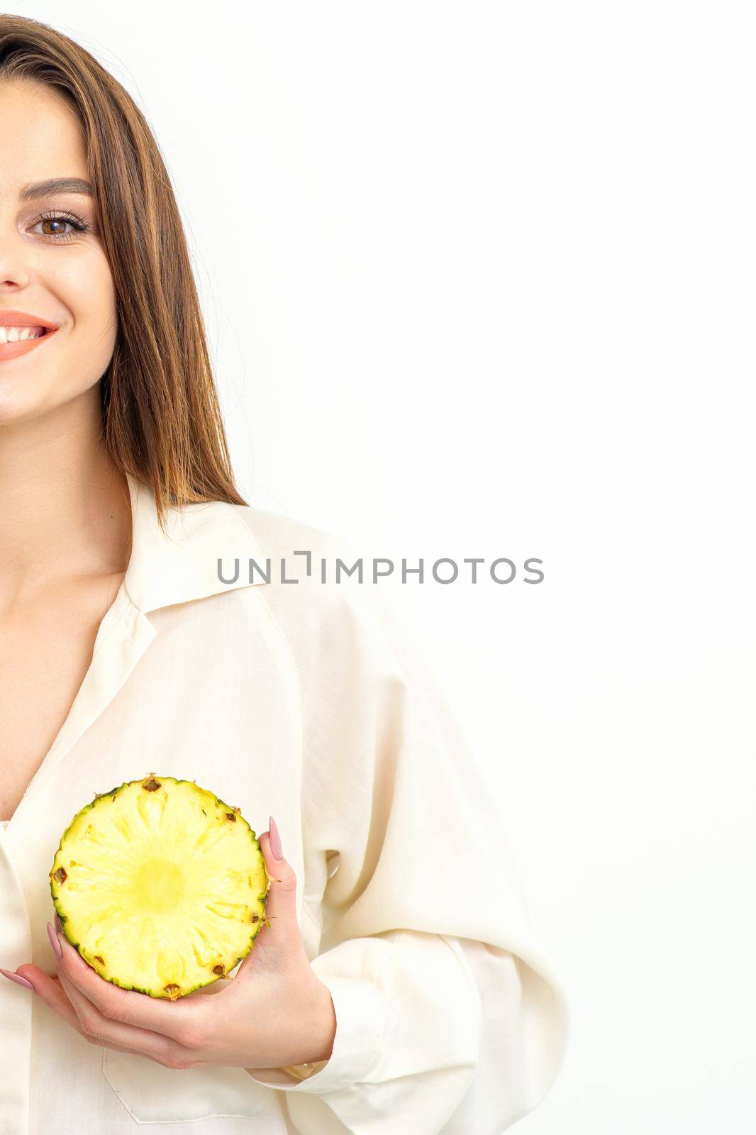 Young Caucasian smiling woman holding slices pineapple over white background, breast health concept. by okskukuruza