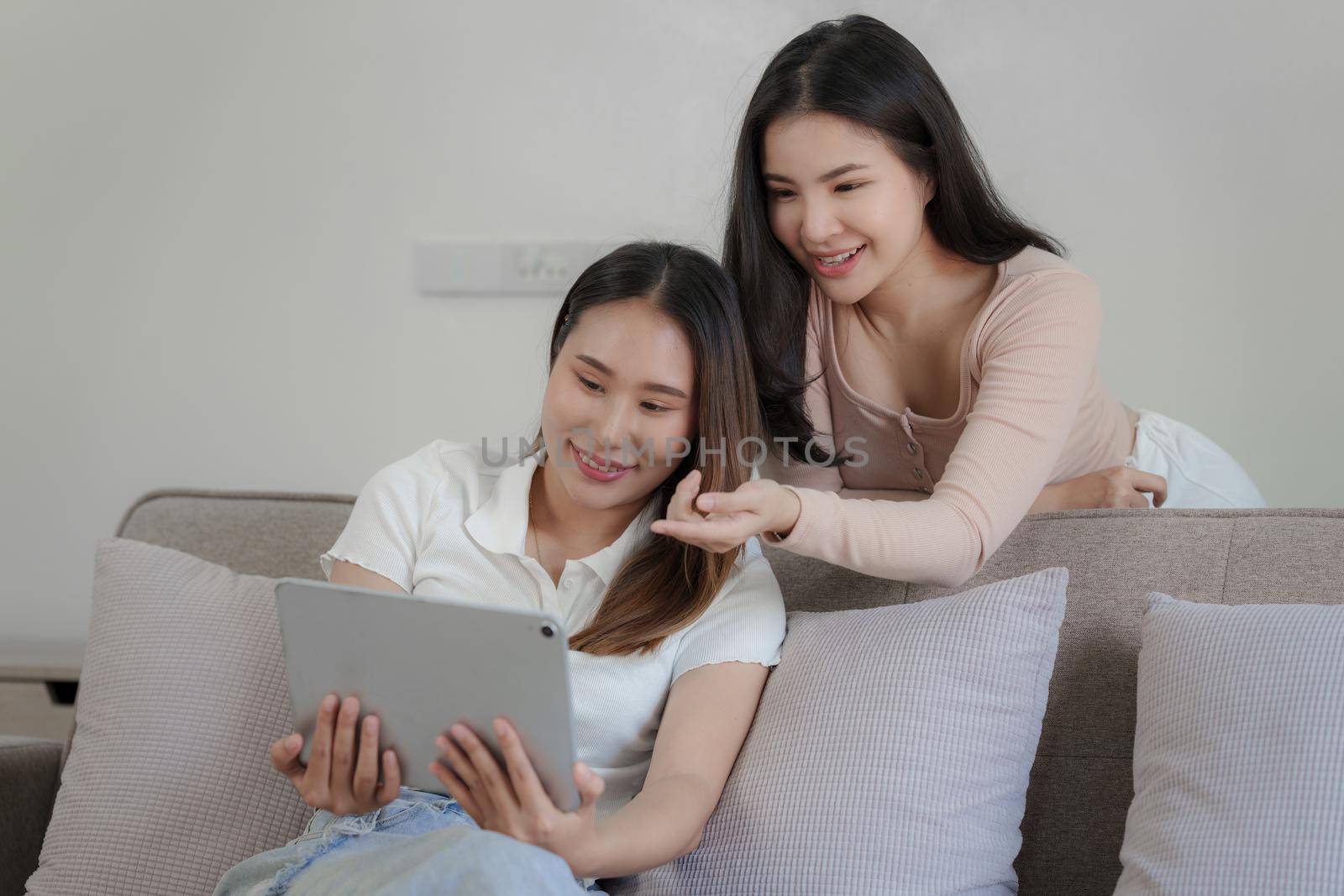 Two asian women having nice lively conversation in living room on sofa in cozy interior by itchaznong