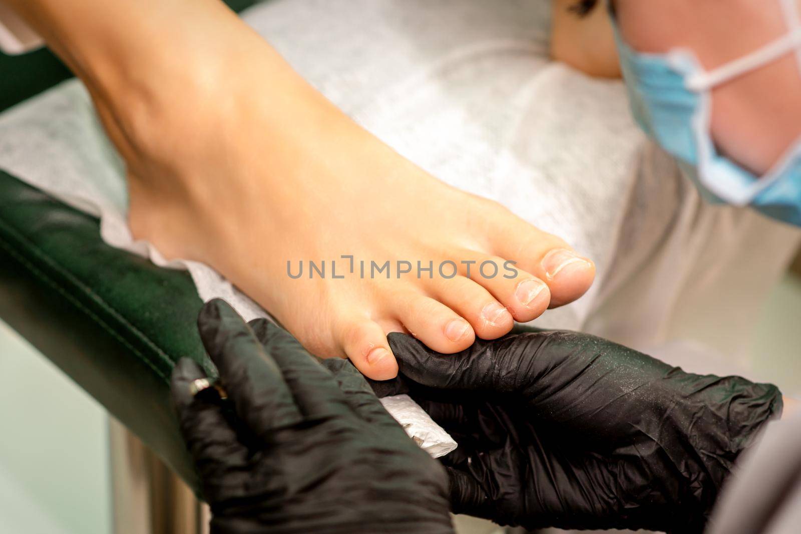 The podiatry doctor examines the toenails on the female foot. by okskukuruza