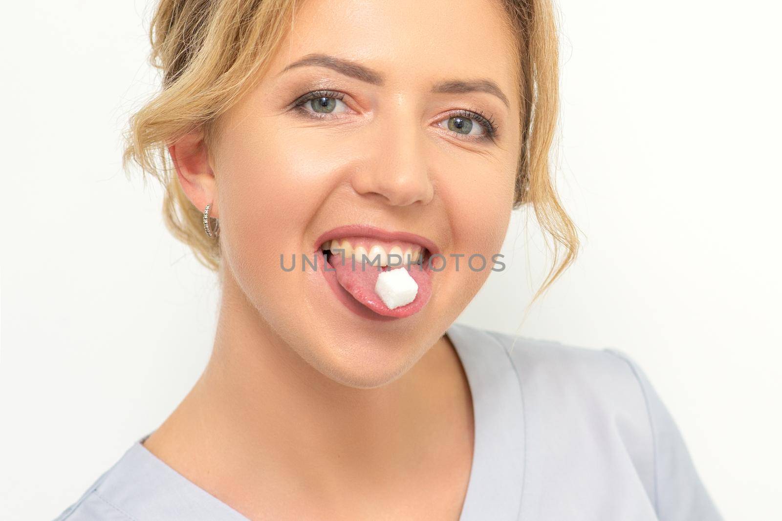 Waxing, depilation, hair removal concept. Happy young caucasian beautician with a sugar cube in her mouth looking at the camera on white background