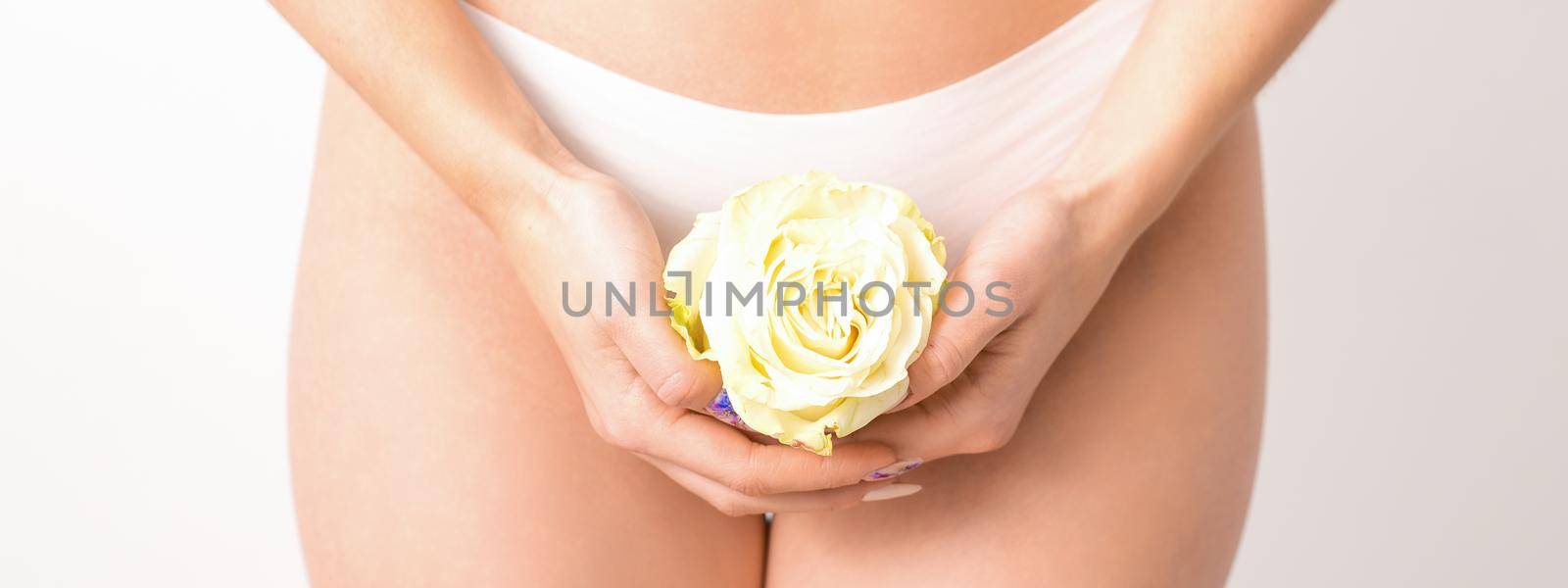 Caucasian woman in white panties with white rose flower on a uniform background, closeup. by okskukuruza