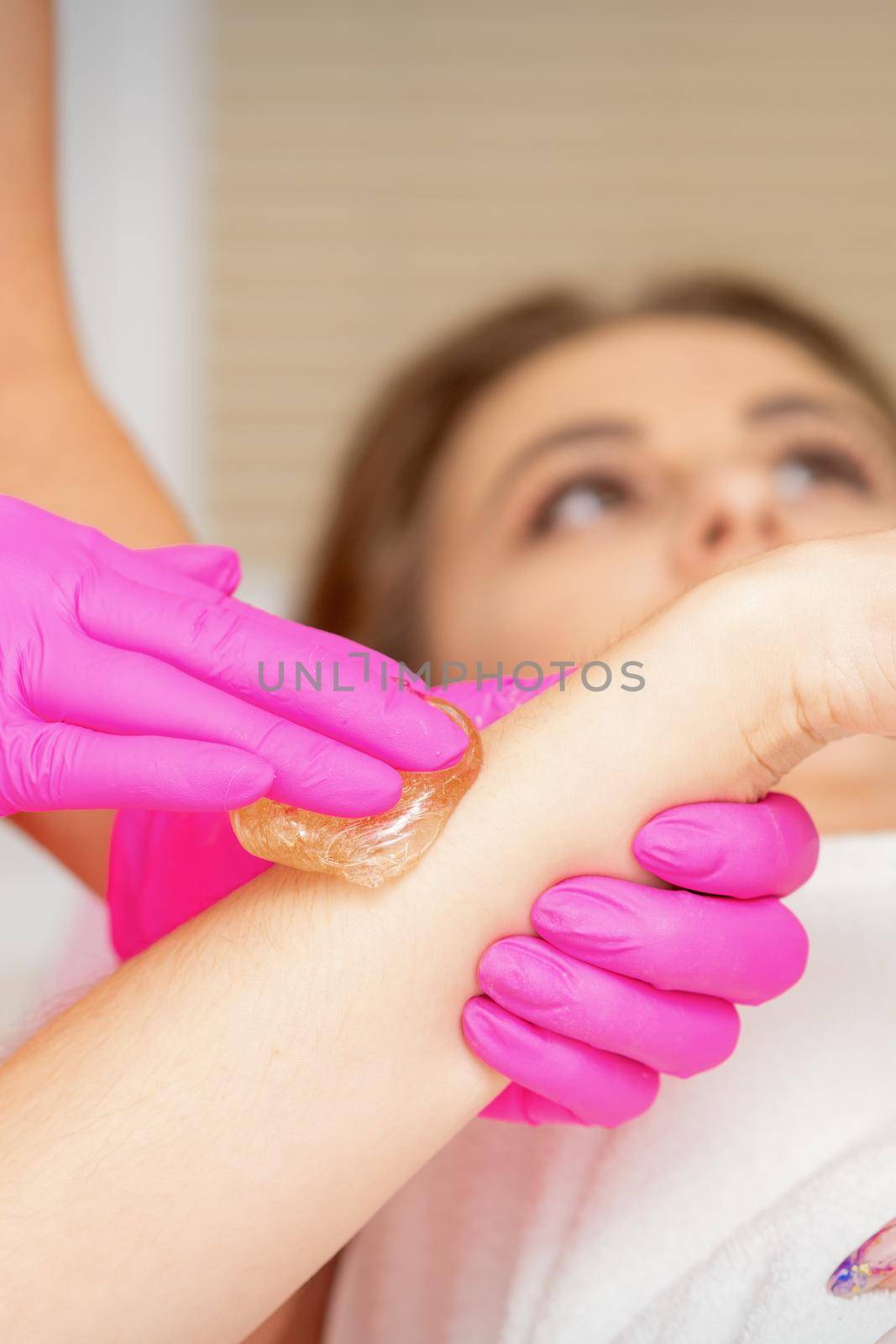 Waxing. Depilation hand and arm of the young woman lying in the spa salon