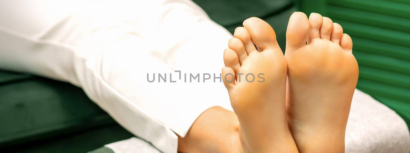 Feet of a young caucasian woman while treatment procedure in a beauty salon. by okskukuruza