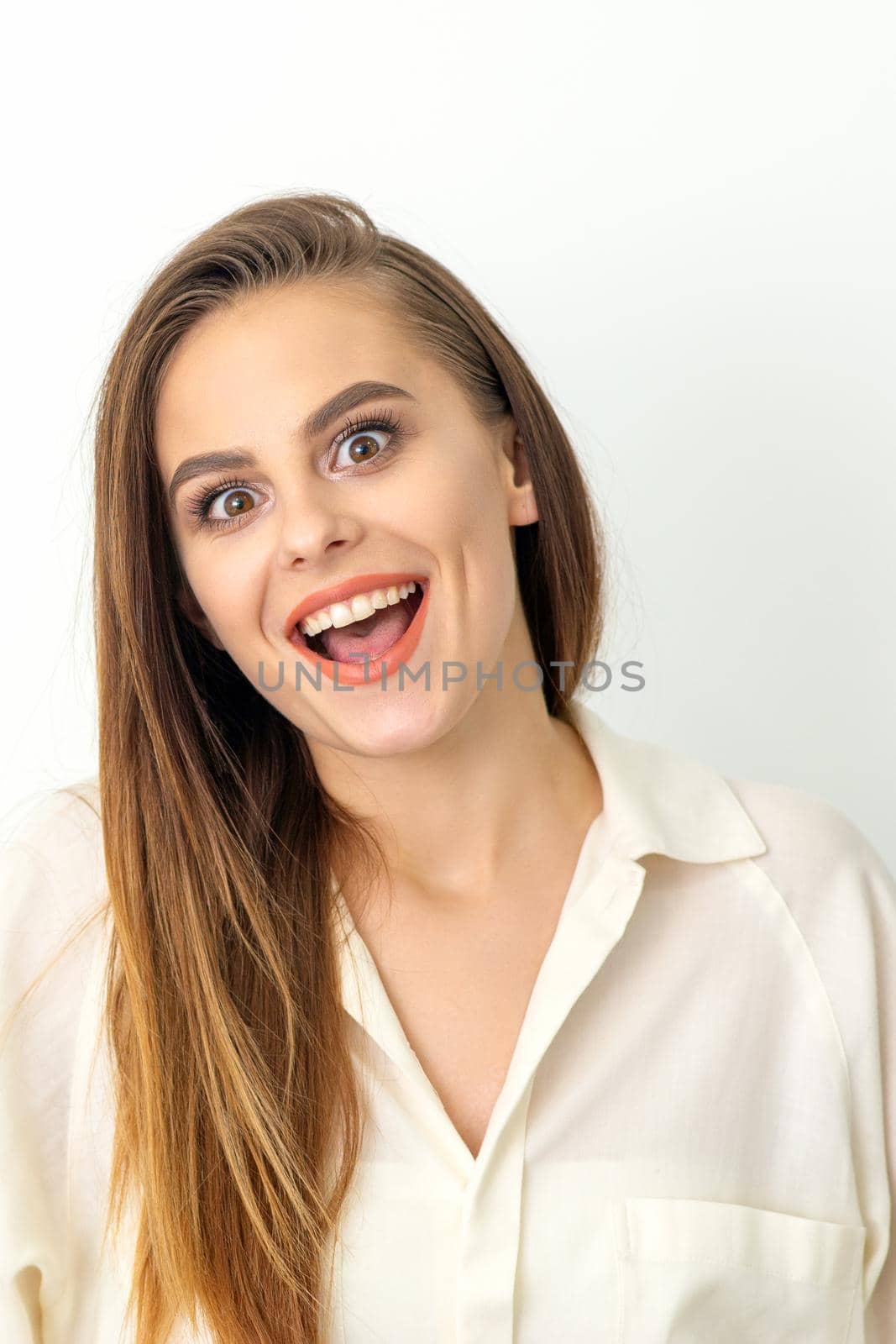 Portrait of a young caucasian happy woman wearing white shirt smiling with open mouth against the white background