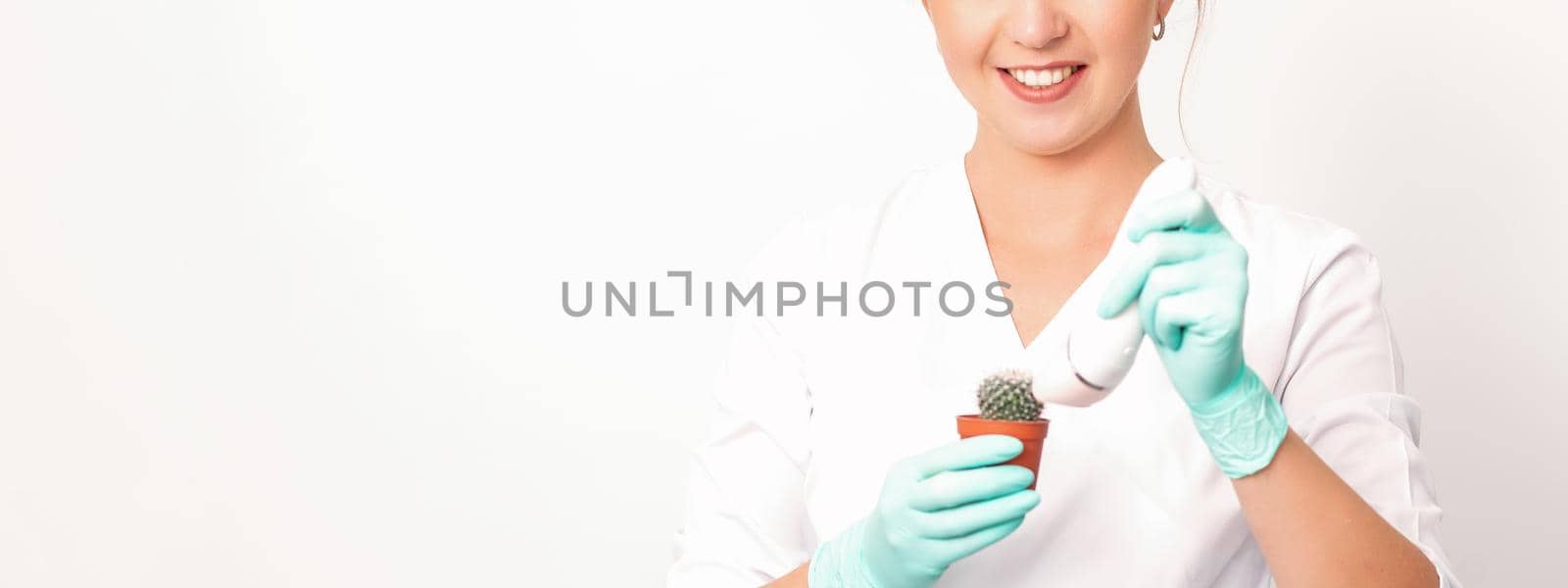 A smiling female beautician holds little green cactus with the razor in her hands. Hair removal concept