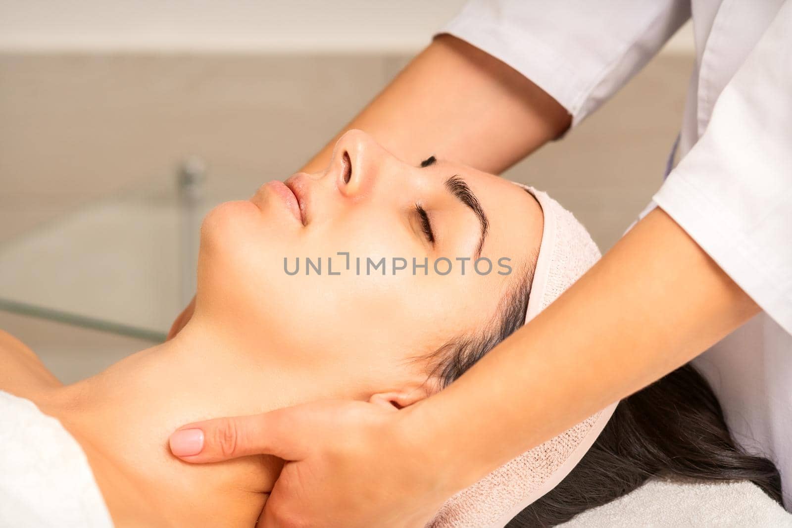 Facial massage. Young caucasian woman getting a massage on her neck in a beauty clinic