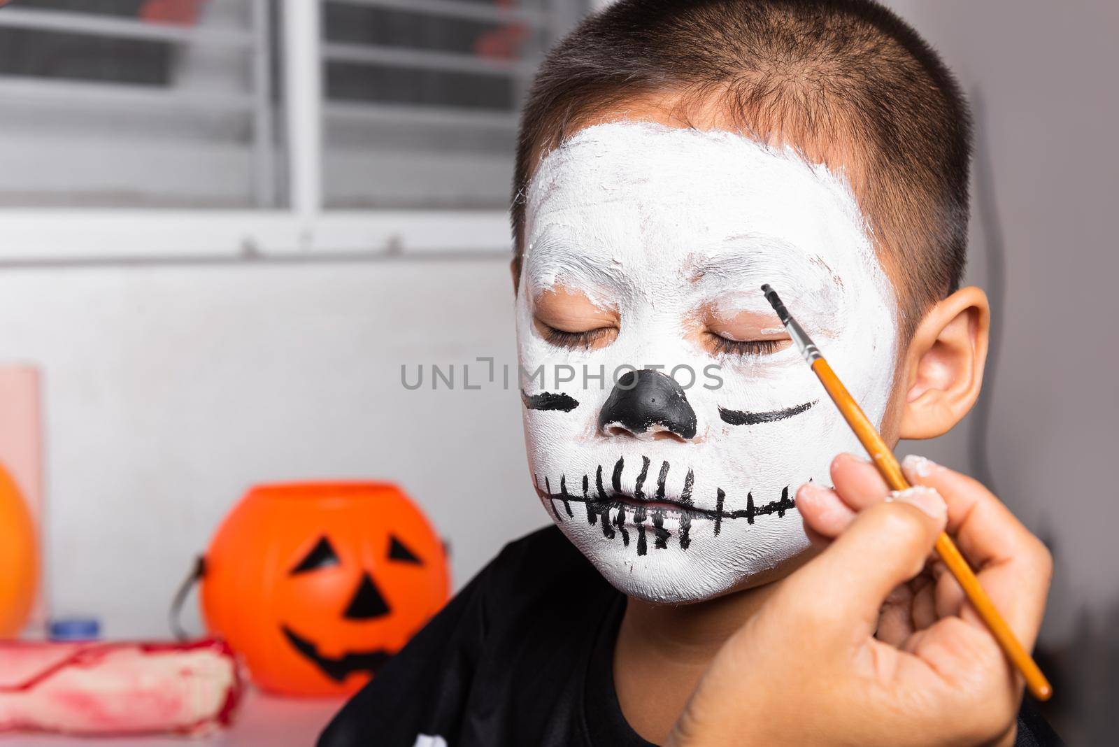 Asian mother and kid son getting makeup halloween face painting look like ghost by Sorapop