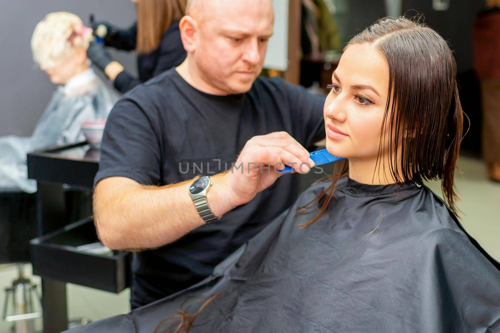 Haircut of long wet hair of young caucasian woman by a male hairdresser in a hair salon